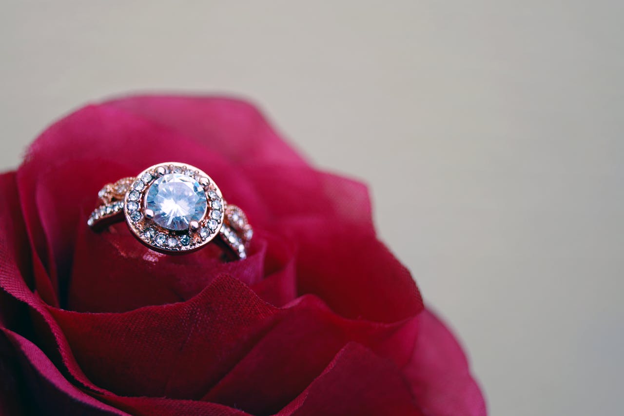 A close-up of an Aquamarine engagement ring sitting inside of a red rose.