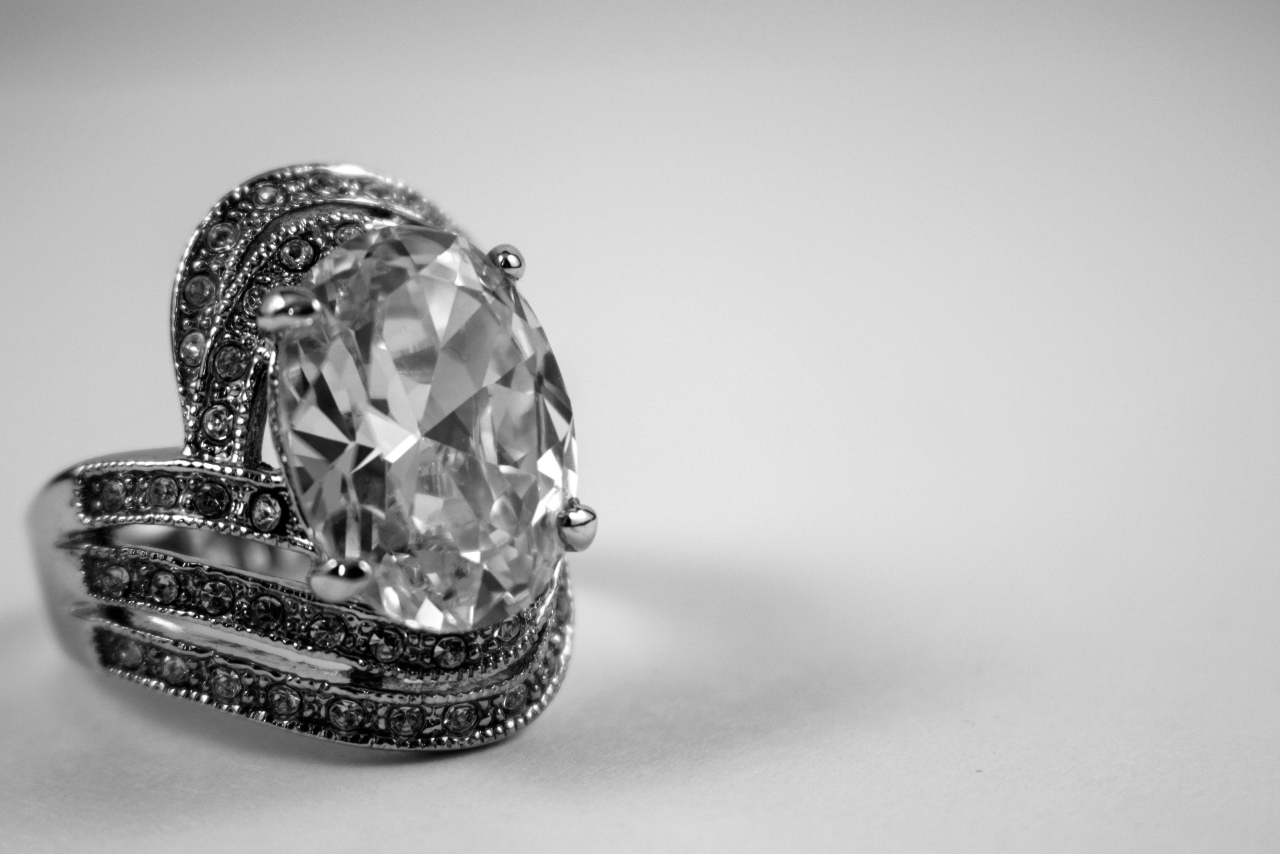 A close-up of a complex engagement ring on a white surface.