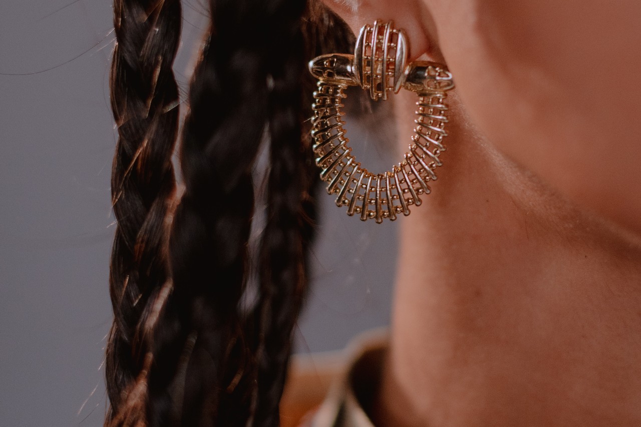 close up image of a person wearing an elaborately designed gold earring