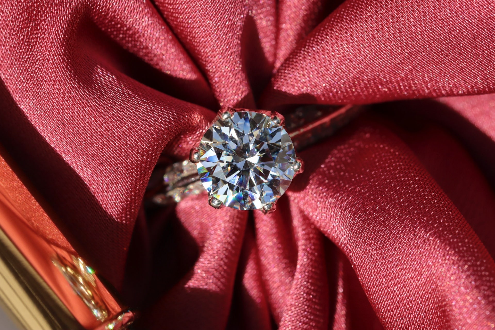 Sparkling round-cut diamond ring showcased on rich red fabric.