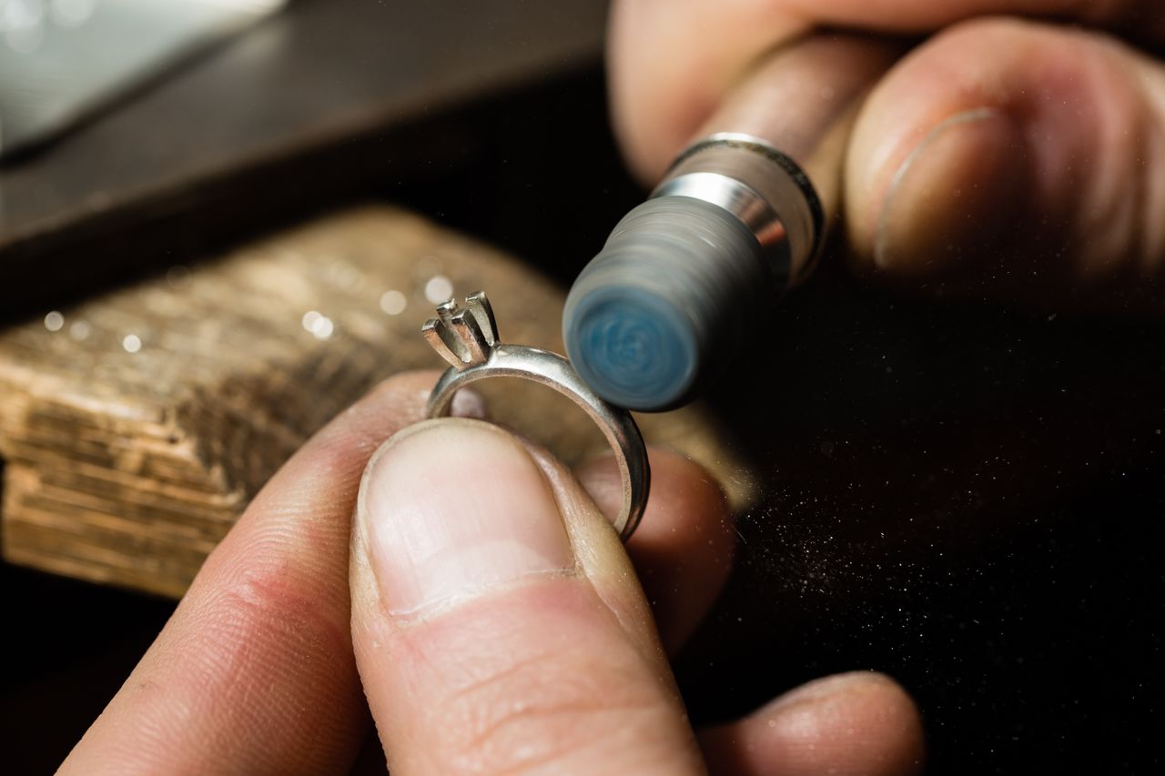 Close-up of a jeweler finishing a diamond ring with a bur.