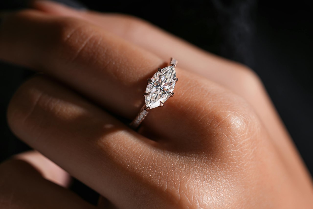 A marquise diamond with an east-west setting on a side stone white gold ring.