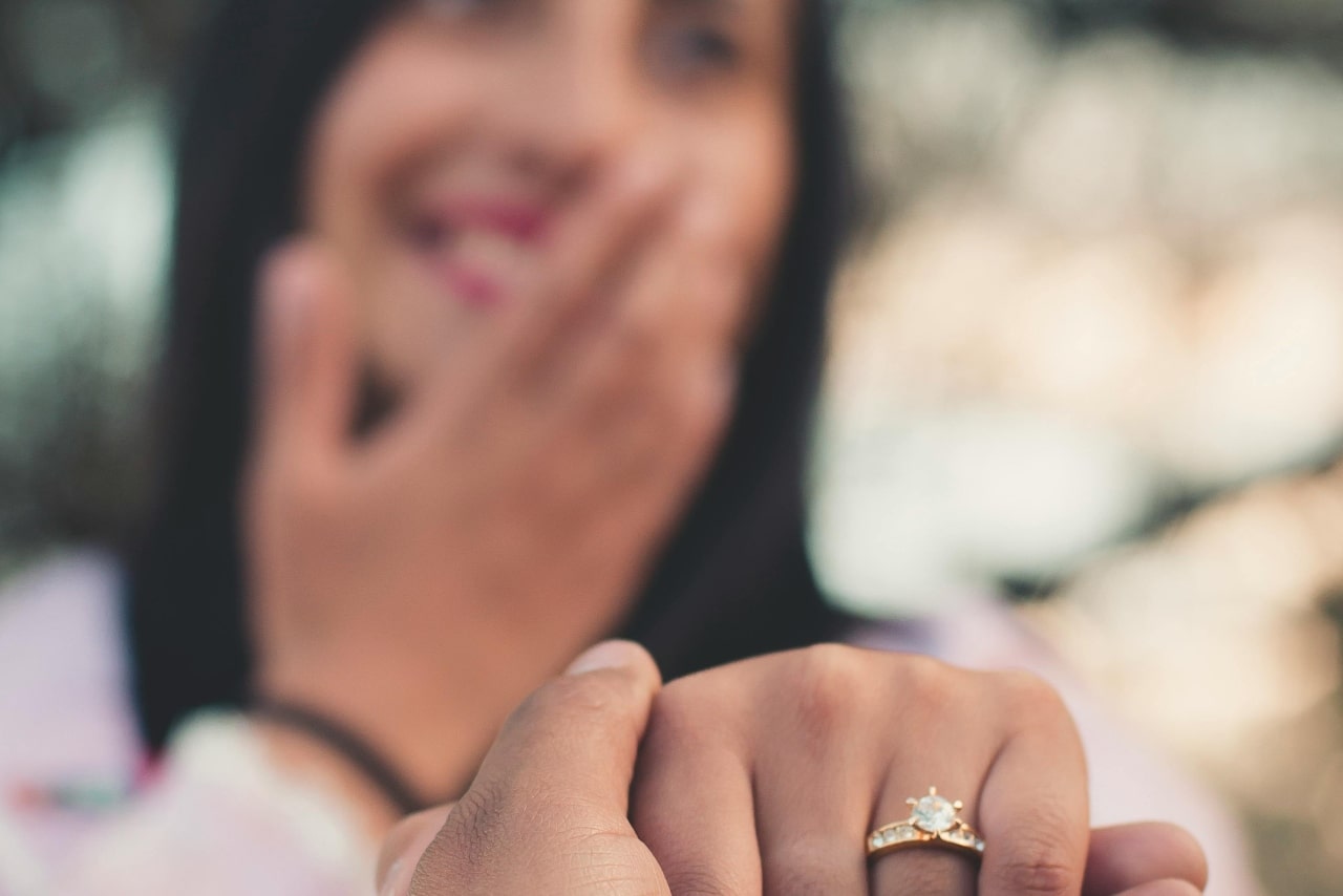 A woman showing off her yellow gold diamond engagement ring right after the proposal