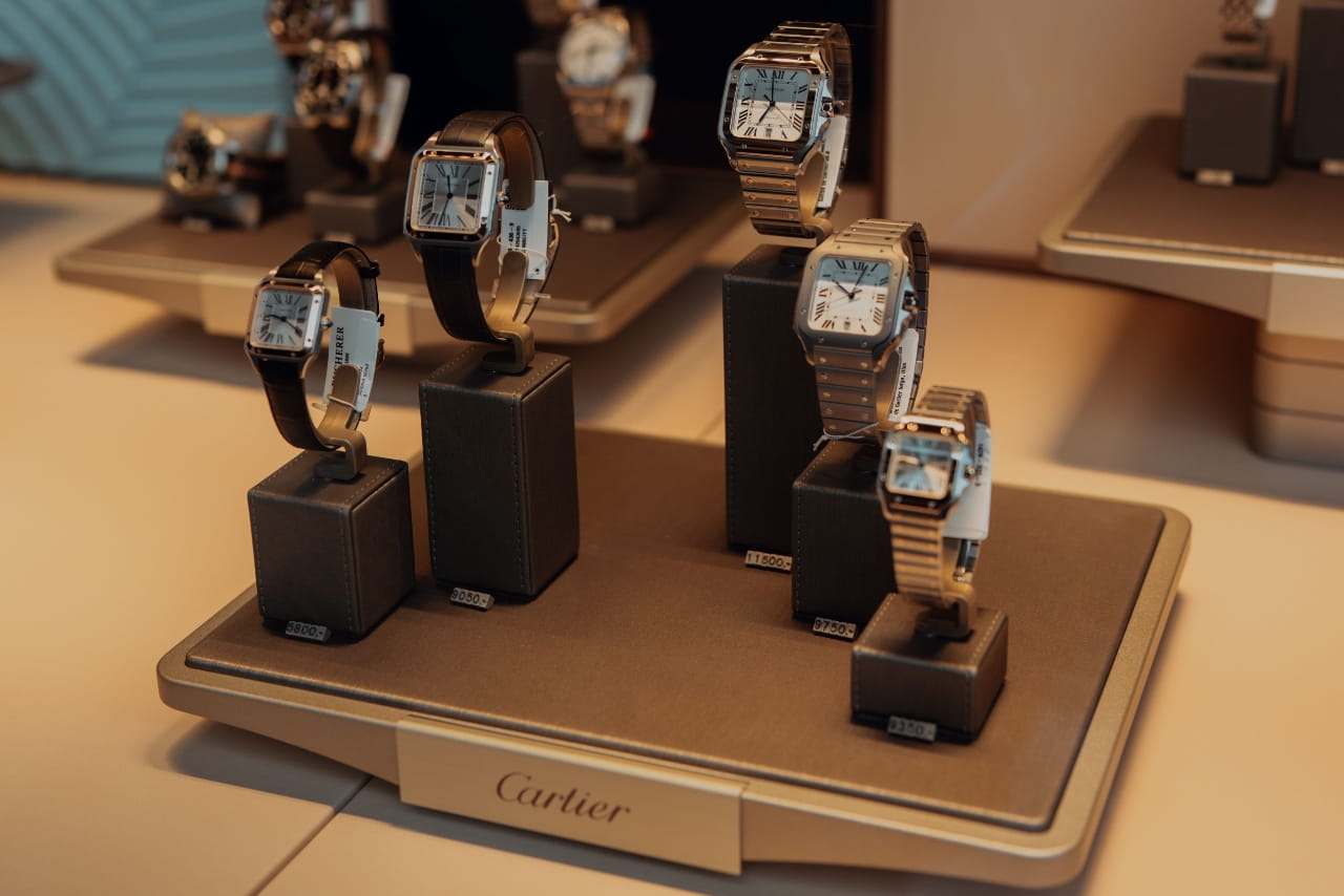 A luxury Cartier store display featuring several Santos de Cartier square watches mounted on individual stands.