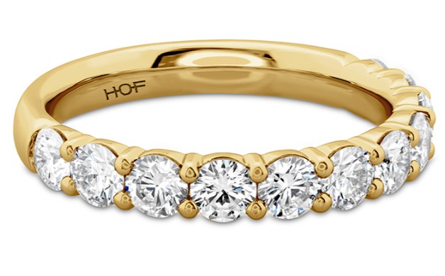 A yellow gold half-way diamond wedding band on a white background