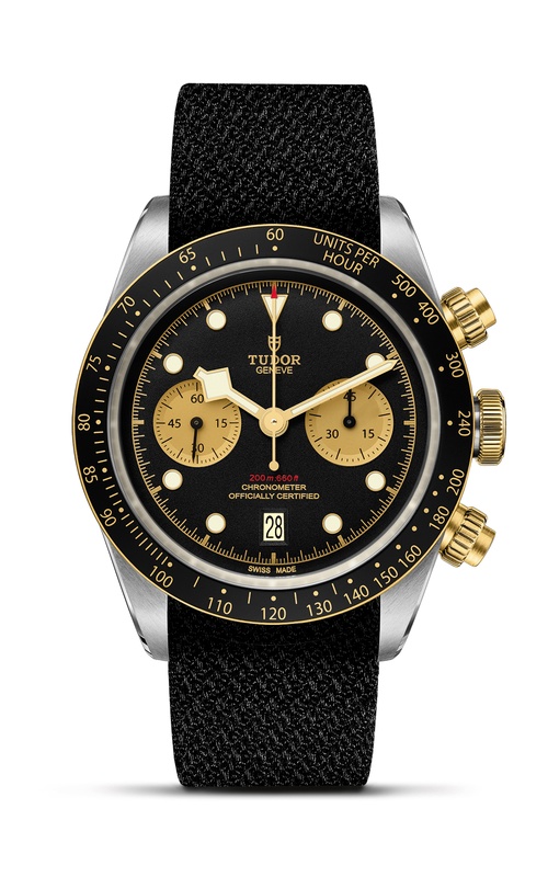 A TUDOR watch with black fabric strap, black dial with gold plated subdials, and bezel with gold accents