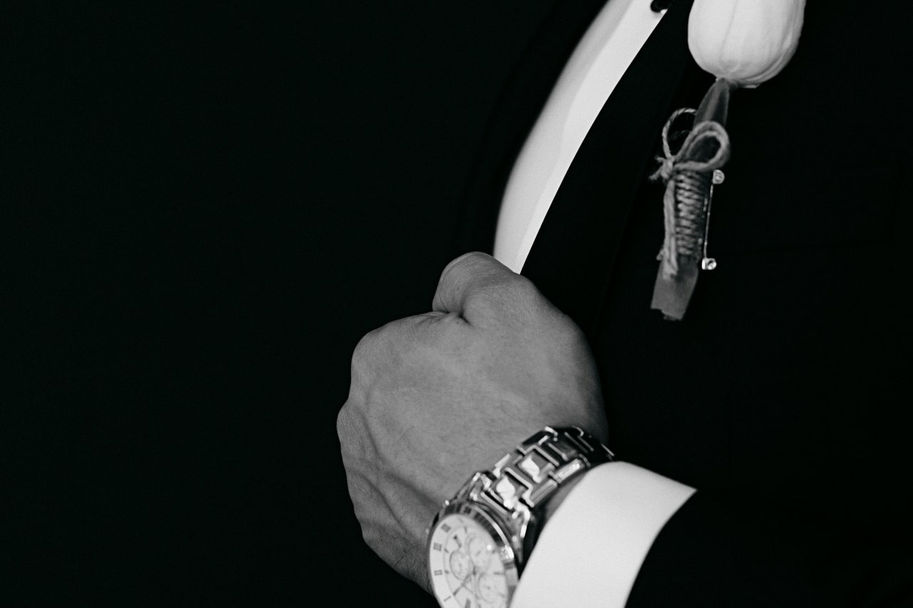 A black and white picture of a man in a suit with a stainless steel watch on his wrist.