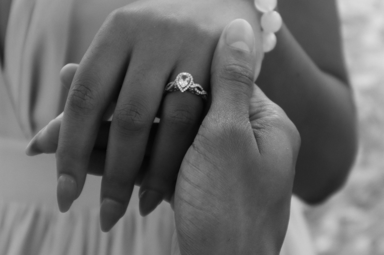 A black and white picture of a woman&rsquo;s held with pear shaped diamond engagement ring with intertwined band