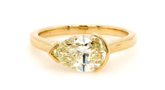 A yellow gold engagement ring with an east to west oriented pear shape center stone, available at Heller Jewelers.