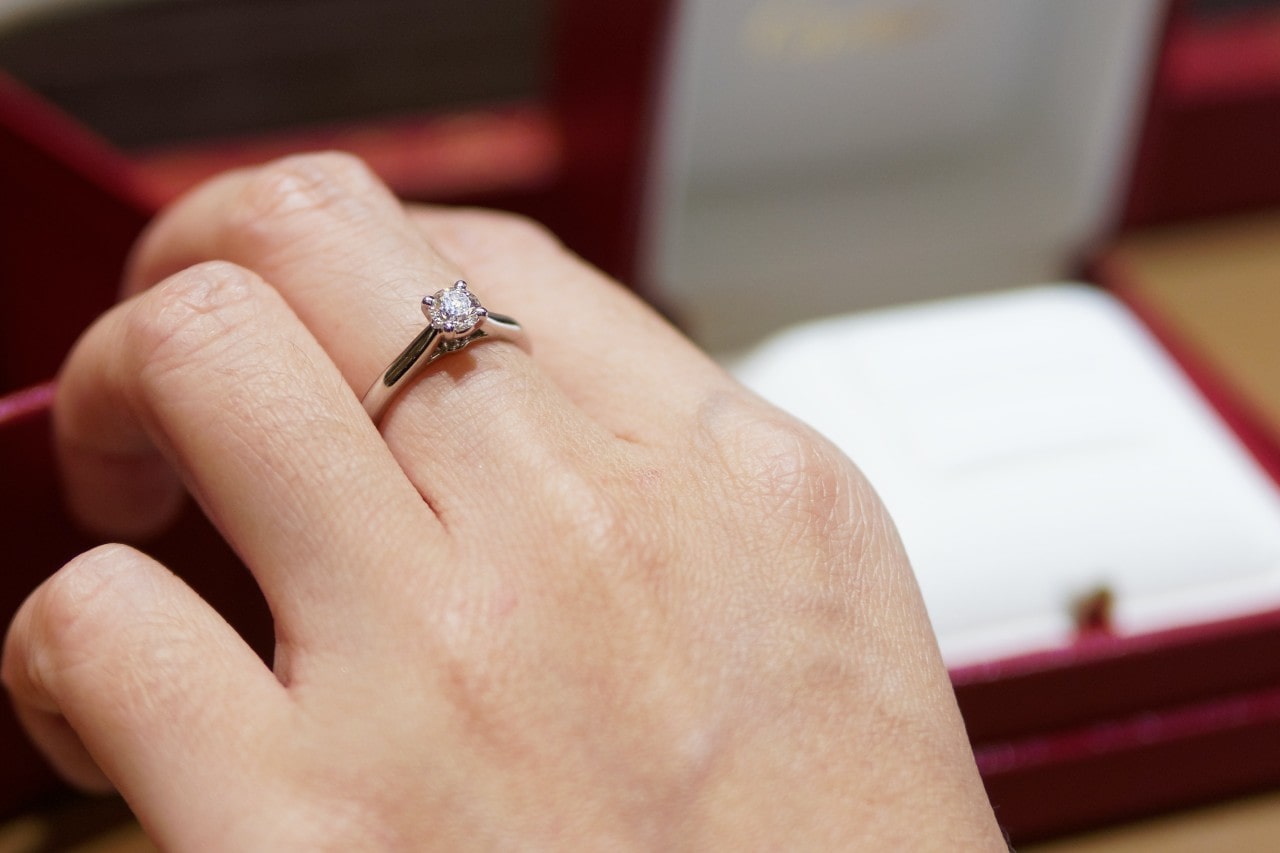 A close-up of a woman’s hand wearing a single, elegant solitaire ring. A close-up of a woman’s hand wearing a single, elegant solitaire ring.