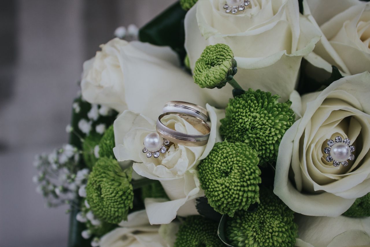 Men’s wedding band sitting atop a myriad of white flowers.