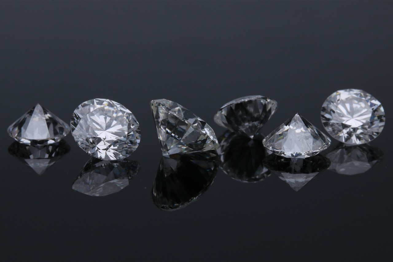 Several loose diamonds on a reflective surface