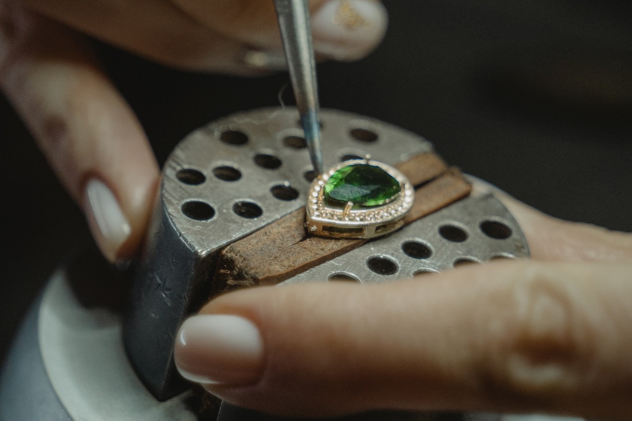 A close up of a pear shaped emerald pendant fixed by a jeweler.