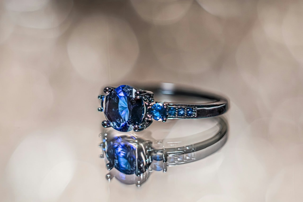 A vibrant blue sapphire ring against a blurred background. A vibrant blue sapphire ring against a blurred background.
