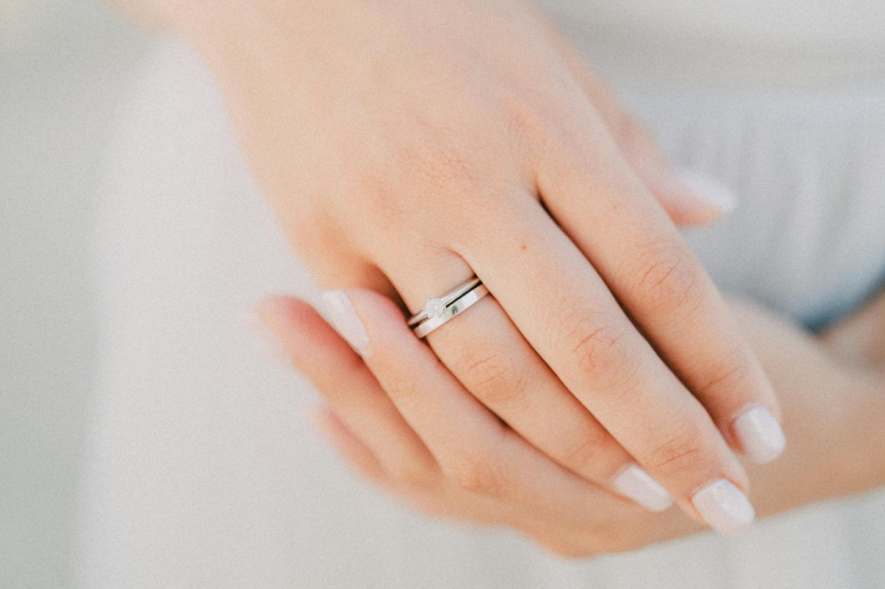A close-up of a woman’s hands, with emphasis on her matching white gold engagement ring and wedding band. A close-up of a woman’s hands, with emphasis on her matching white gold engagement ring and wedding band.
